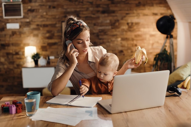 Blijf thuis moeder communiceert via mobiele telefoon terwijl ze thuis werkt