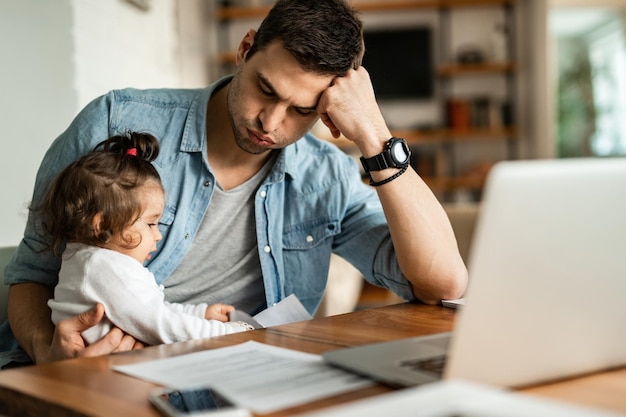 Blijf thuis vader voelt zich moe terwijl hij probeert te werken en op zijn kleine dochter past