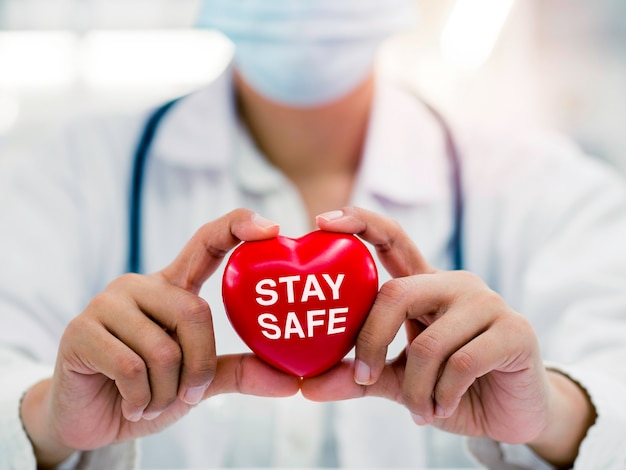 Blijf veilig, gezondheidszorg en geneeskunde concept. Close-up van vrouwelijke artsenhanden die het rode hart vasthouden met het woord Stay Safe, Campagne voor mensen om thuis te blijven voor de veiligheid van de pandemie van het Coronavirus.