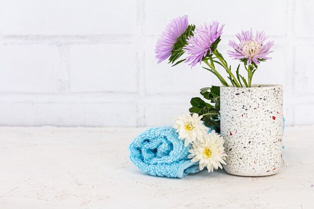 Blikje met bloemen van aster en handdoeken op een witte ondergrond