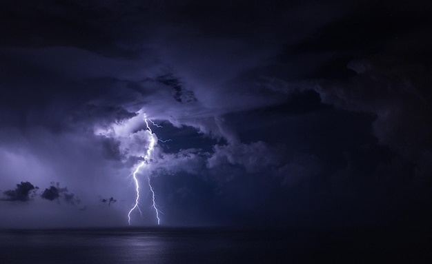 Bliksem over de zee tegen stormwolken in de hemel's nachts