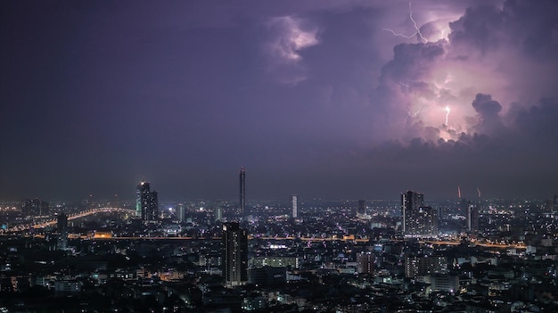 Bliksem over verlicht stadsbeeld's nachts