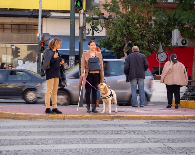 Слепая девушка переходит дорогу по пешеходному переходу с помощью собаки-поводыря в Греции
