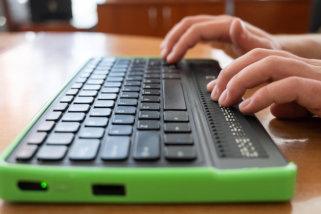 A blind man uses a computer with a Braille display and a computer keyboard Inclusive device