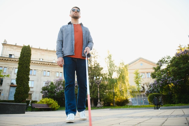 Photo blind man walking on sidewalk holding stick