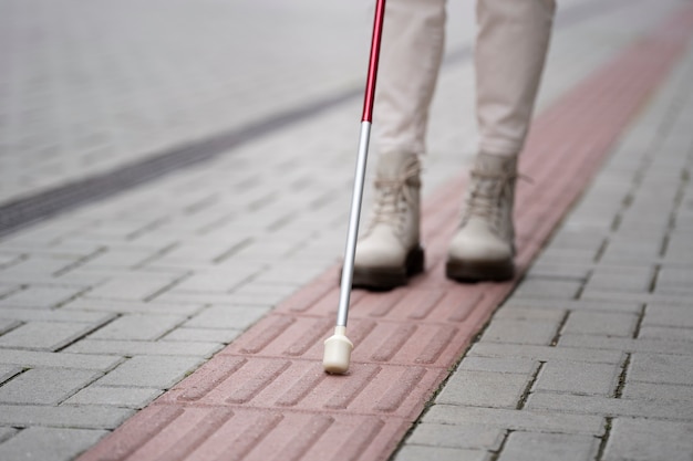 Photo blind person walking through the city with blind stick