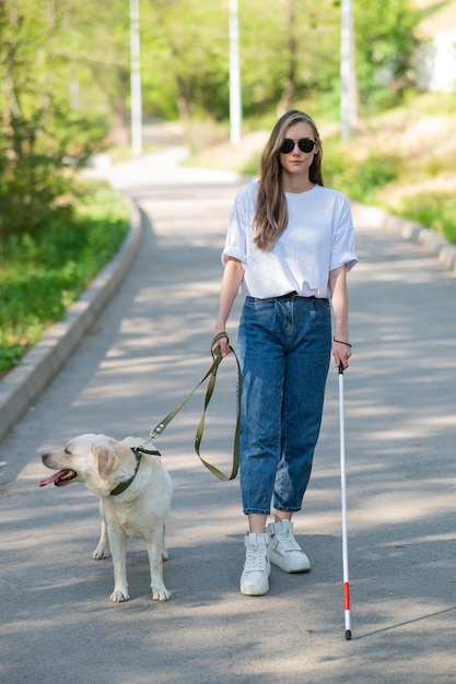 Blind woman walking with guide dog in the park