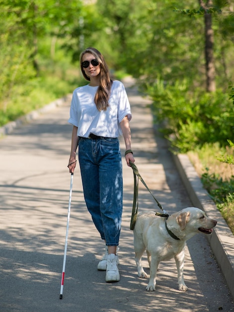 Blind woman walking with guide dog in the park