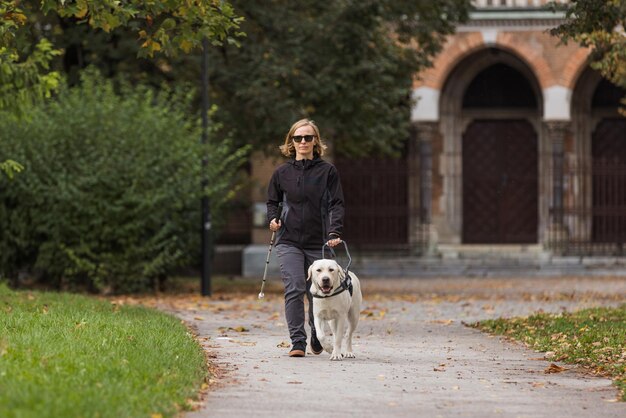 Blinde vrouw die in een stadspark loopt met de hulp van een gidshond