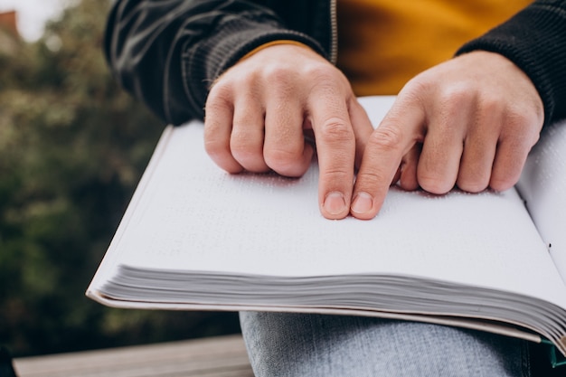 Foto uomo accecato che legge toccando il libro braille