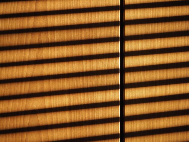 Blinds shadow on wooden wall background