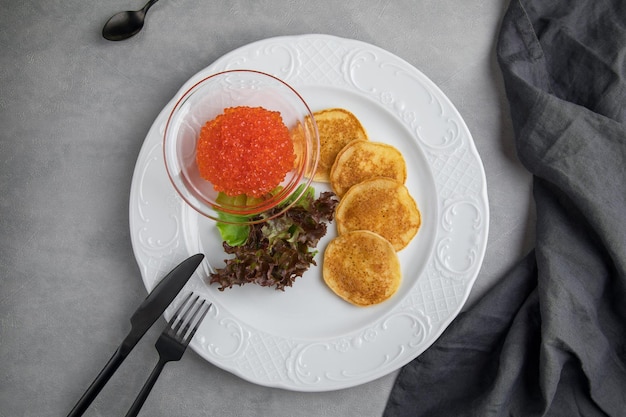 Blini Pancake and Red caviar white plate on a grey background Russian blini carnival pancakes