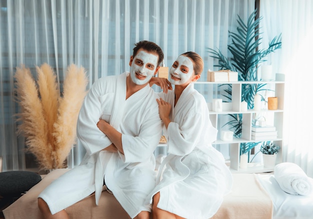 Photo blissful couple in bathrobe with facial cream mask quiescent