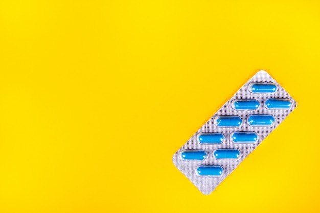 Blister of blue capsules on yellow background