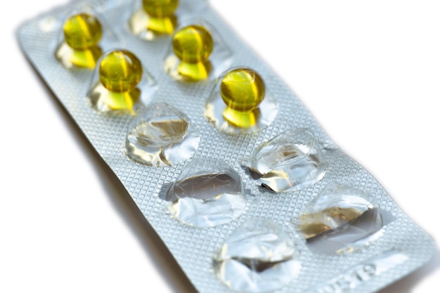 Blister pack of round yellow pills on an isolated white background Half empty pill pack Vitamins A and E capsules in a package