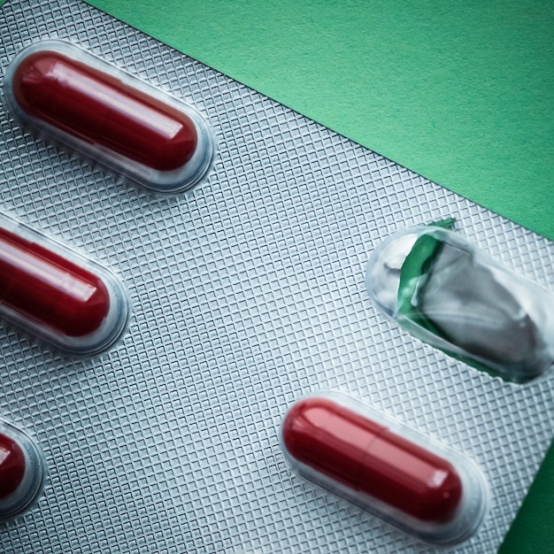 Blister with dark red tablets on a green background.