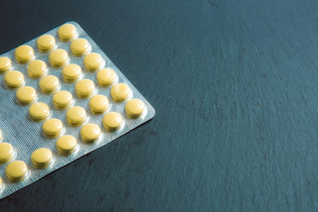 Blister with small pills lying on the dark grey background. Copy space stock photo