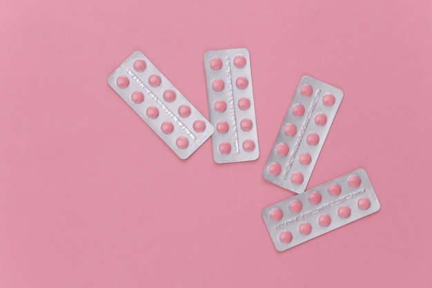 Blisters of pills on a pink background. Top view