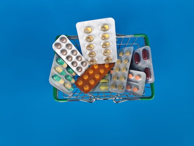 Blisters with pills lying near empty toy shopping basket