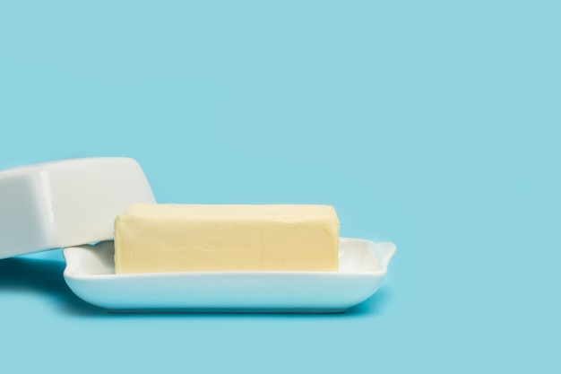 A block of butter on an open white butter dish