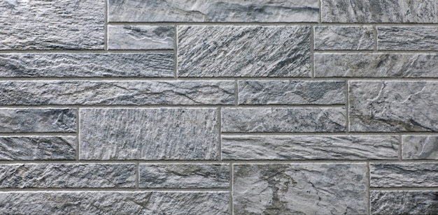 The blocks of solid stoneThe wall of gray stoneVintage rustic weathered uneven background