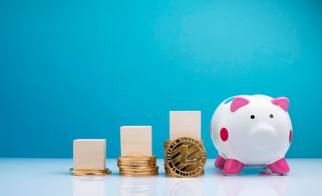 Photo blocks on stacked coins by piggy bank over table against blue wall