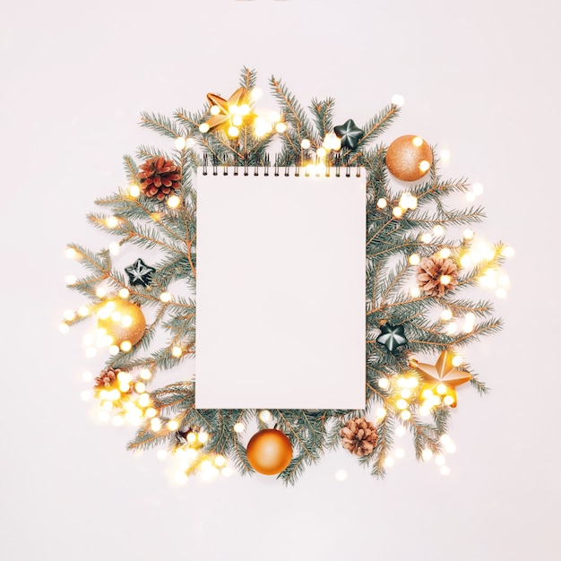 Foto blocnote met vakantiedecoratie in groene en gouden kleuren op witte achtergrond, copyspace. kerstmis en nieuwjaar planning flatlay concept.