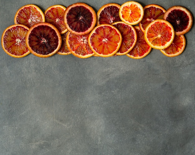 Bloed sappige Siciliaanse oranje plakjes op grijze achtergrond. Gesneden bloedsinaasappeltextuur. Citrus achtergrond.
