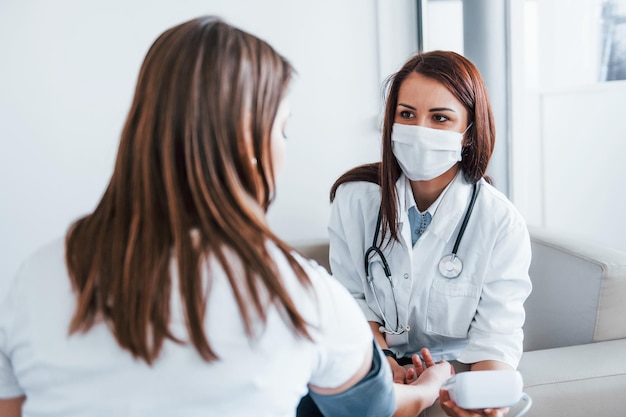 Bloeddruk meten Jonge vrouw heeft een bezoek aan een vrouwelijke arts in een moderne kliniek