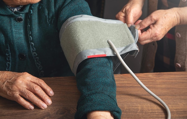 Foto bloeddrukmeting van een oudere vrouw thuis