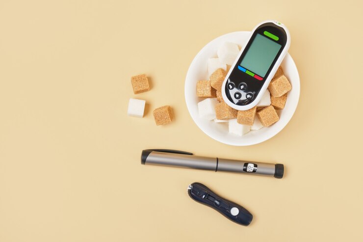 Bloedglucosemeter, lancet, insulinespuitpen en suikerklontjes in een witte kom op een beige achtergrond, bruin riet en witte suiker