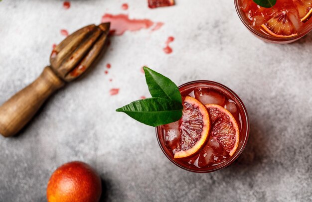 Bloedsinaasappelsap met ijs en sinaasappelplak. frisse zomer cocktail met rode sinaasappels in een glas.