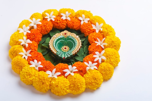 Bloem Rangoli voor Diwali Festival gemaakt met goudsbloem en blad en olielamp op een witte achtergrond