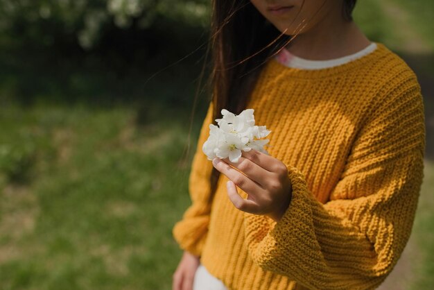 Bloemen in de hand van een onherkenbaar tienermeisje in een geel jasje