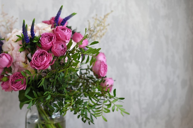 Bloemen in een glazen pot op grijze betonnen achtergrond. Vintage woondecoratie. Kopieer ruimte voor tekst.