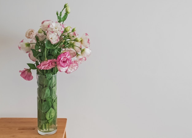 Bloemen in een glazen vaas die bij de muur staat