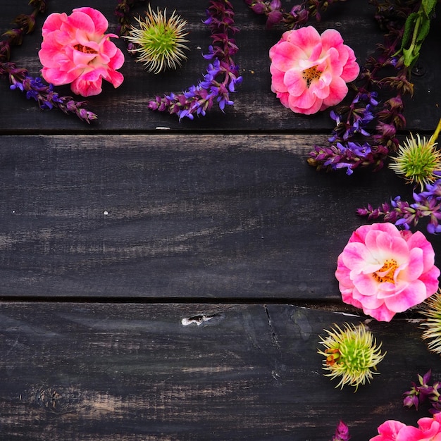 Bloemen in een halve cirkel op een houten achtergrond Briefkaart voor de vakantie Rozen lavendel salie en harige kastanjes langs de randen op donkere planken Achtergrond kopie ruimte plat lag Feestelijke poster