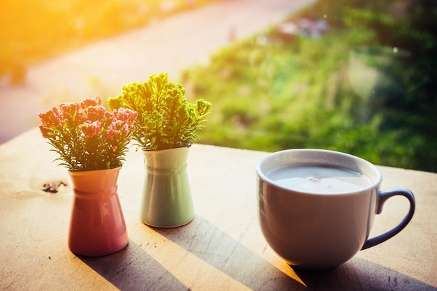 Foto bloemen in een vaas en een kop koffie op de rustieke achtergrond