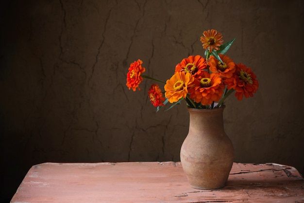 Bloemen in kruik op oude houten tafel