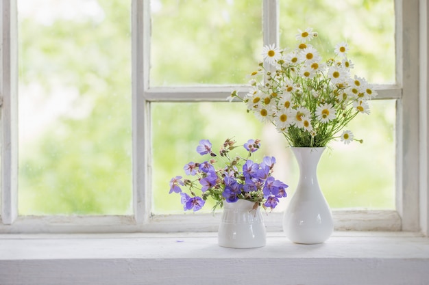 Bloemen in vazen op vensterbank