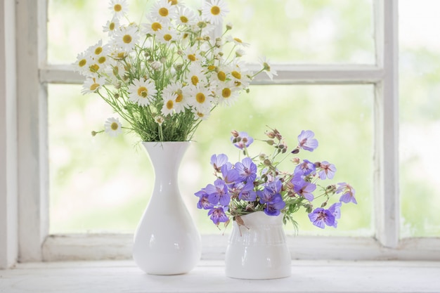 Bloemen in vazen op vensterbank