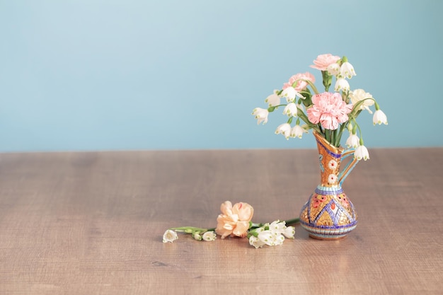 Bloemen in vintage kruik op houten tafel op blauwe achtergrond