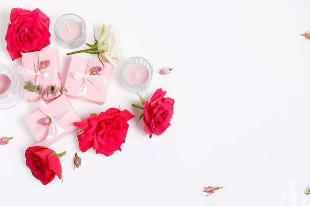 Bloemen samenstelling. Roze cadeau en rood roze bloemen op witte achtergrond. Bovenaanzicht, plat lag, kopieer ruimte. Verjaardag, Moederdag, Valentijnsdag, Dames, Trouwdag concept.