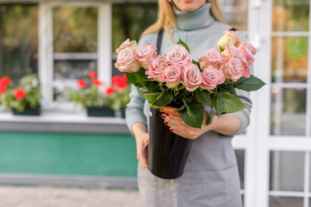 Bloemenwinkel bij daglicht. een vrouw houdt een mooi boeket bloemen vast