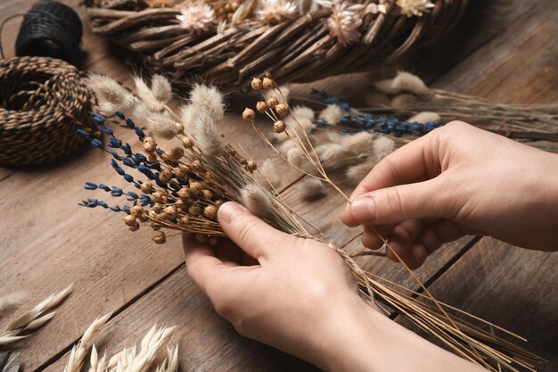 Foto bloemist boeket gedroogde bloemen maken op houten tafel close-up