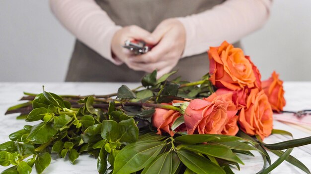 Bloemist die rode rozen snoeit voor boeketarrangement.