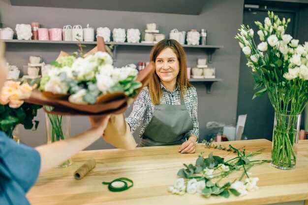 Bloemist geeft vers boeket aan vrouwelijke klant in bloemenboetiek.