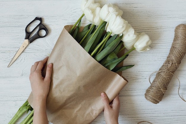 Bloemist maakt een boeket van witte tulpen, bovenaanzicht