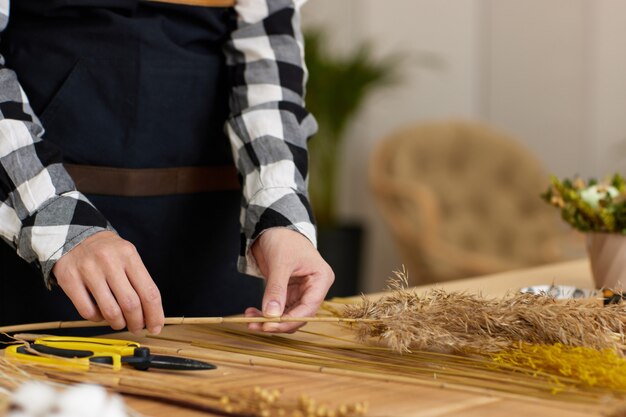 Bloemist maakt mooi boeket gedroogde bloemen op houten tafel, close-up