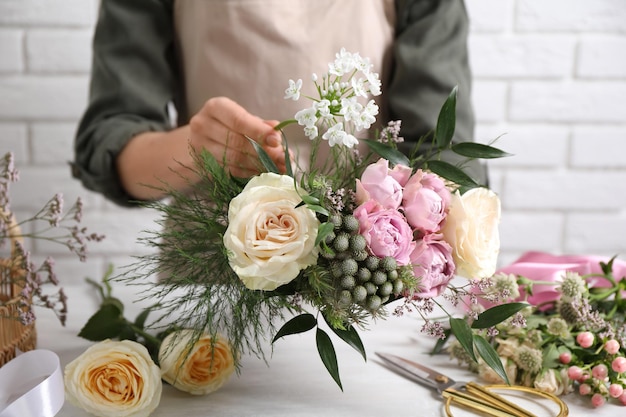 Bloemist mooi boeket maken aan witte tafel close-up